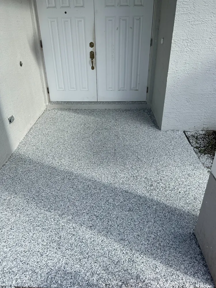 Finished gray flake coating on a front patio leading to white double doors